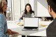 © Maria Vitkovska - Smiling positive business people, friends working in modern office, sitting at desk, using laptop