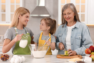 Canvas Print - Three generations. Happy grandmother, her daughter and granddaughter cooking together in kitchen