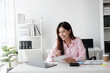 © Parichat - Young adorable Asian businesswoman working with laptop computer while holding document.