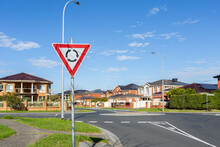 Roundabout Sign Before Road Intersection In Suburbia