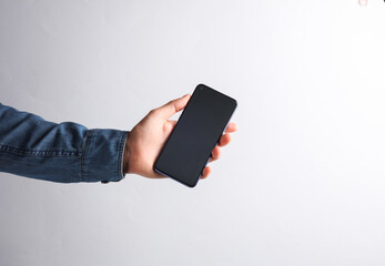 Wall Mural - Hand in a denim shirt holding a smartphone on a gray background