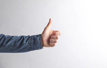 Man's hand in a denim shirt shows a thumbs up on a gray background