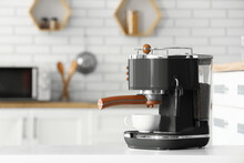 Modern Coffee Machine With Cup On White Table In Kitchen