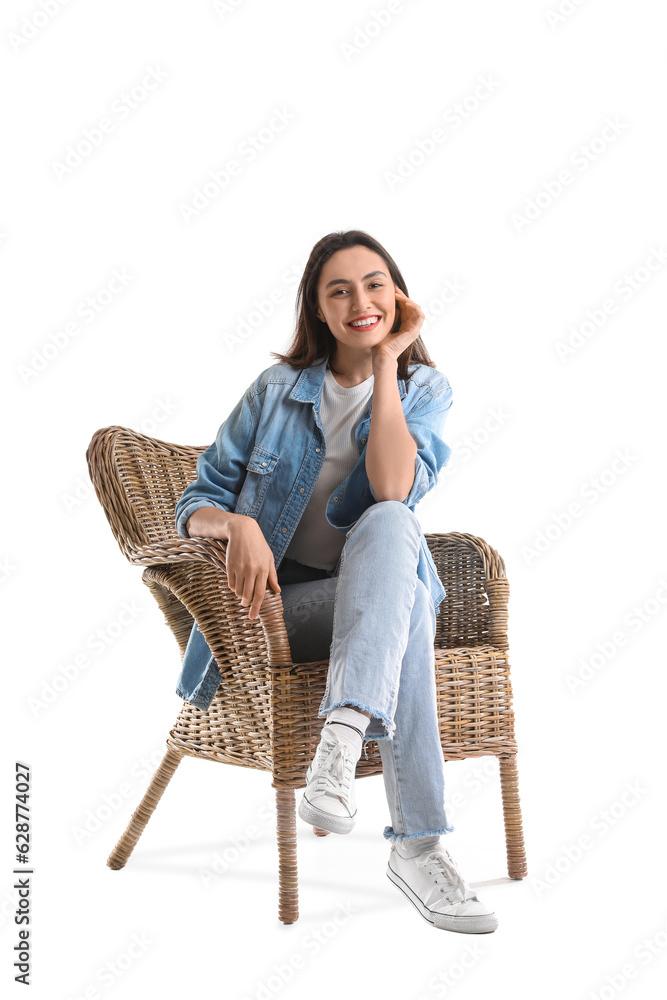 Young woman sitting in wicker armchair on white background