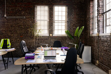 Modern Creative Office Interior With Exposed Brick Walls, Desks And Chairs