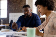 © Wavebreak Media - Focused diverse male and female architects discussing blueprints sitting at desk in office