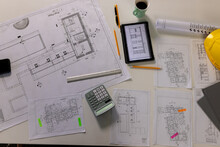 Overhead View Of Desk With Architectural Blueprints, Tablet, Coffee And Hardhat