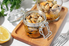 Board With Jar And Glass Bowl Of Pickled Mussels On White Background
