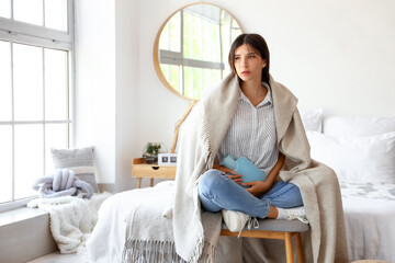 Canvas Print - Young woman with hot water bottle suffering from menstrual cramps in bedroom