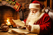 © Виктория Марьенко - Santa Claus reads a letter with a wish list for Christmas at home near the fireplace