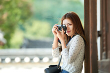 A Young Woman Wearing A Camera And Taking Pictures While Traveling To Tourist Attractions With Traditional Korean Houses