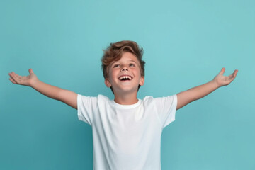 boy kid in a white t-shirt joyfully raises his arms, his vibrant energy shining against a captivating blue backdrop, portraying an aura of positivity and exuberance