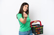 © luismolinero - Young Brazilian woman holding a shopping basket full of food isolated on white background making money gesture