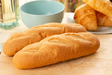 Fresh Baked French Bread And Croissants On A Wooden Table In The Kitchen.
