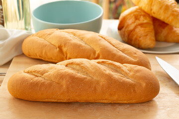 Wall Mural - French bread and croissants on a wooden table in the kitchen