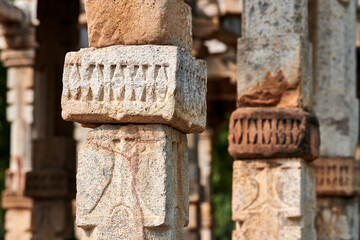 Stone columns with decorative bas relief of Qutb complex in South Delhi, India, close up pillars in ancient ruins of mosque landmark, popular touristic spot in New Delhi, ancient indian architecture