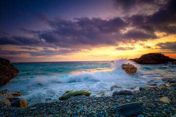 Wall Mural - Sunrise time at the sea. Sea Ocean.  Big roks. Wave hit the rock at beach, sea water splash up to the sky with sun. Sunset Sundown at Sea. Storm.