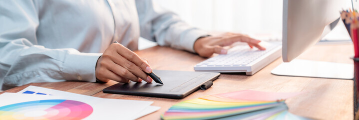 Leinwandbilder - Graphic designer work on computer laptop and with graphic drawing pen while brainstorming unique design with professional graphic team in modern digital studio workplace. Panorama shot. Scrutinize