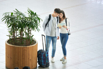 A couple dragging suitcases and looking at a map at a Korean train station