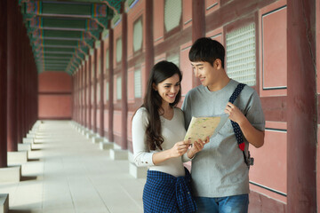 A college student couple looking for their way through a map during a trip to a traditional Korean house