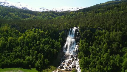 Wall Mural - Drone landscape of Tvindefossen waterfall with a green forested hill view on a sunny day