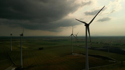 Canvas Print - Aerial view of windmills on green countryside fields at sunset with dramatic sky