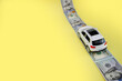 White toy car on money road on yellow background with copy space