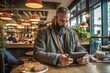 © thesweetsheep - Man using tablet while sitting in coffee shop.