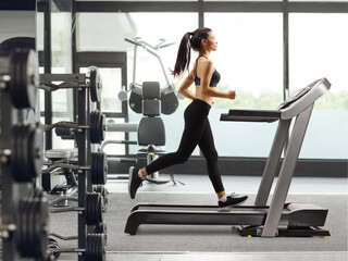 Sticker - Young woman running on a treadmill at a gym