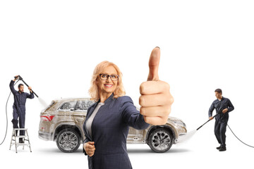 Wall Mural - Happy mature woman with a SUV gesturing thumbs up at a carwash