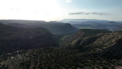 Poster - Drone scene around rocky canyon mountains with grass under blue cloudy sky on the horizon