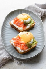 Close-up shot of a  plate with two slices of fresh bread with vegetables , meat and eggs on it