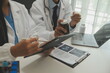 © Sirikarn Rinruesee - Confident doctor man holding a pill bottle and writing while talking with senior patient and reviewing his medication at office room.