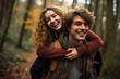 Happy young man carrying his beautiful smiling pretty woman on his back at the park, having fun together. Boyfriend giving piggyback ride on shoulder to his beautiful girlfriend in autumn. High