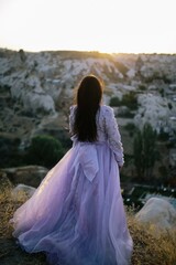 Sticker - Young woman with long, flowing dress on a hilltop, admiring the majestic mountain range