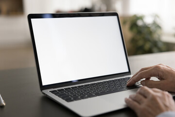 Empty white laptop display on work table of mature business freelance woman. Cropped shot of senior customer lady typing on computer with copy space on blank screen. Cropped close up shot