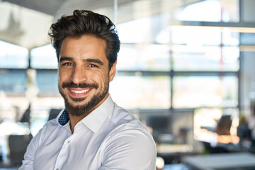 Wall Mural - Happy young Latin business man standing in office, headshot close up portrait. Smiling Hispanic businessman manager, successful entrepreneur, male professional executive looking at camera.