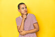 © Asier - Shaved head woman in red striped tee, yellow backdrop thinking and looking up, being reflective, contemplating, having a fantasy.