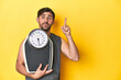 Athletic man with scale, on a yellow studio backdrop having some great idea, concept of creativity.