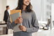© Maria Vitkovska - Cropped view of the smiling Indian woman wearing casual clothes holding laptop and documents at modern office. Concept of successful business