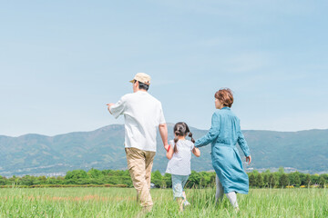 春・夏に公園・草原を歩く家族・ファミリーの後ろ姿（子供・両親・移住・田舎暮らし）
