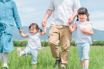 Poster - 両親と手を繋いで歩く姉妹の子供
