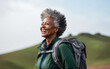 Leinwandbild Motiv Black african american dark-skinned happy senior woman hiking outdoors. Fitness walking and forest travel journey. Active senior person concept
