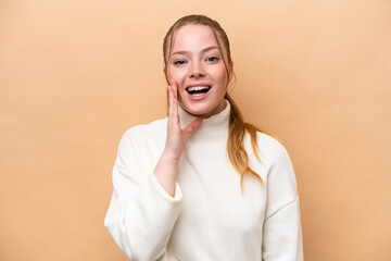 Wall Mural - Young caucasian woman isolated on beige background with surprise and shocked facial expression