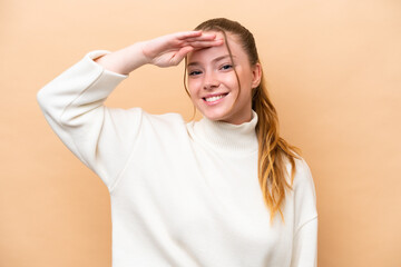 Canvas Print - Young caucasian woman isolated on beige background saluting with hand with happy expression