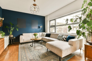 a living room with blue walls and white furniture, including a large plant in the corner of the room on the right side