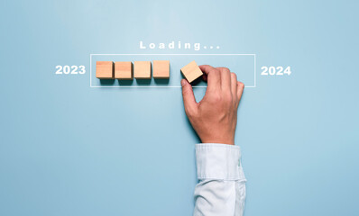 Wall Mural - businessman assembly wooden block in progress bar for loading new year 2023 to 2024 concept.