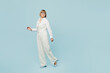 © ViDi Studio - Full body side view employee business woman 50s wears white classic suit glasses formal clothes walking going look aisde on area isolated on plain pastel blue background. Achievement career concept.