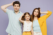 © ViDi Studio - Young shocked sad amazed parents mom dad with child kid daughter girl 6 years old wear blue yellow casual clothes look camera hold scratch head isolated on plain purple background. Family day concept.