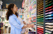 © Taras Grebinets - Charming pregnant woman designer, artist choosing color vibrant cardboard sheets on the shelves in a creative art store